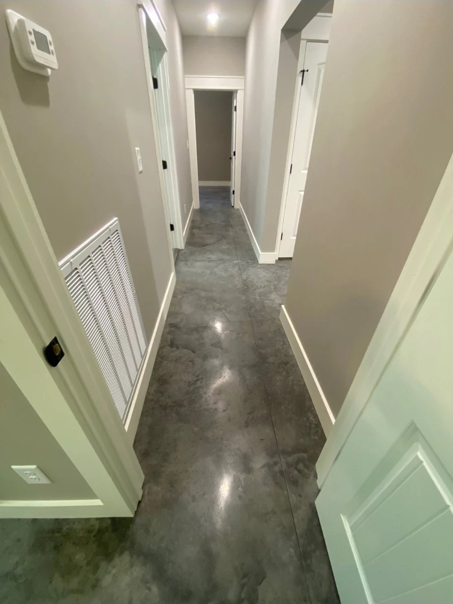 Hallway with a stained, polished concrete floor, white trim and doors leading to bedrooms and a bathroom