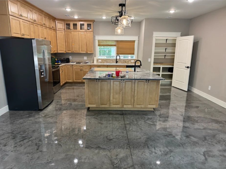 Open kitchen with light wood cabinets, granite counters, a stainless refrigerator, pendant lighting and a stained, polished concrete floor